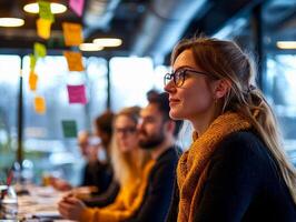 Focused woman in meeting, engaged with team discussion, modern workspace, bright mood. photo