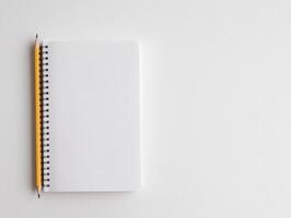 Blank spiral notebook with a yellow pencil on a white isolated background. photo