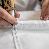 Close-up of hands sewing fabric with sewing machine on a white background. photo