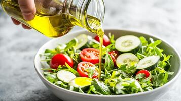 Pouring olive oil over a fresh salad with arugula, tomatoes, and cucumbers. photo