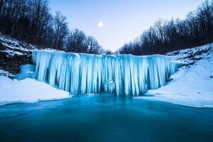 Frozen waterfall during winter under a clear night sky with a full moon. photo