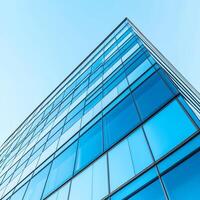 Modern glass building with blue reflections under clear sky. photo