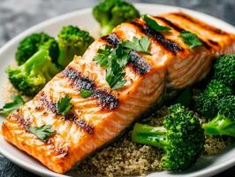 Grilled salmon fillet served with broccoli and quinoa on a white plate. photo
