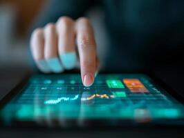 Finger touching digital tablet with financial data graphs on screen. photo
