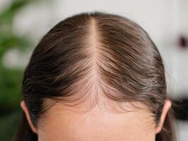 Close-up of a woman's hair parting displaying hair texture and style. photo