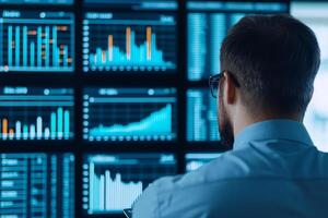 Man observing financial data on multiple screens in a modern office environment. photo