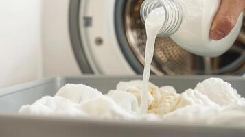 Pouring laundry detergent into a washing machine with clean white clothes. photo