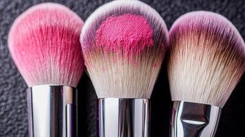 Three makeup brushes with pink bristles on a textured background. photo