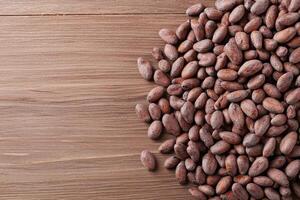 Cocoa beans scattered on a wooden surface, natural texture and rich colors. photo