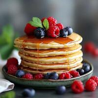 Stack of fluffy pancakes drizzled with syrup and topped with fresh berries. photo