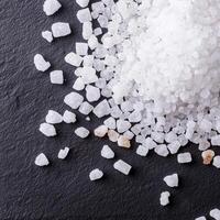 Salt crystals scattered on a dark stone surface, white isolate background photo