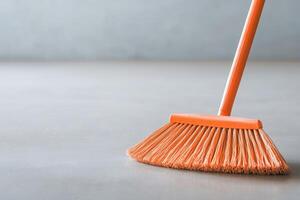 Orange broom on a gray surface, perfect for cleaning tasks and household maintenance. photo