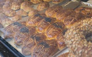 Many different pastries lie behind a glass window of a bakery shop photo
