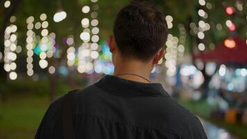Lonely man walking alone through the night market with neon lights on the bokeh street in the background. Sadness, depression, getting fired, A man wearing glasses walking forward in the night city. video