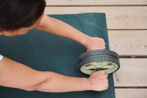 Person exercising with abdominal roller on yoga mat outdoors for core strength and fitness routine photo