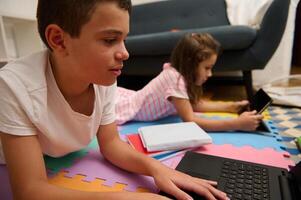 Children enjoying digital learning on the floor with tablets and laptops photo