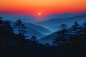 Sunset Over Majestic Mountain Range with Layers of Mist and Silhouetted Pine Trees photo