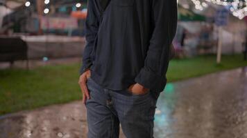Asian man wearing glasses walking forward in the night city with his hands in his pockets with neon lights on the bokeh street in the background. Sadness, depression, getting fired. video