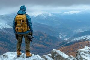 A Photographer Standing on a Snowy Mountain Peak Overlooking a Valley photo