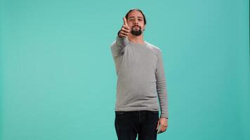 Joyous man showing thumbs up sign gesturing, exulting positive emotion and satisfaction. Radiant person being excited, doing approving hand gesture, isolated over studio backdrop, camera A video