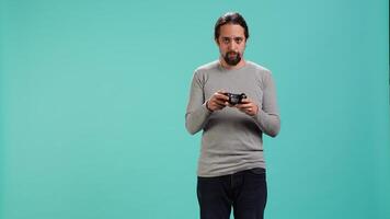 Portrait of man playing videogames holding controller, isolated over studio background. Gamer focused on gaming, participating in PvP online multiplayer game using console system, camera A video