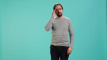 Portrait of man feeling exhausted from overworking, suffering from headache, isolated over studio background. Tired person feeling pain from fatigue, studio backdrop, camera A video