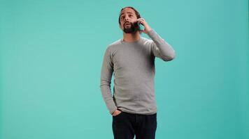 Man discussing with best friend over telephone call using smartphone, studio backdrop. Person talking with mate in phone call using cellphone, isolated over studio background, camera A video