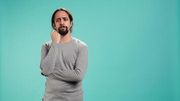 Pensive man deep in thoughts, doing ruminating hand gesturing, isolated over studio background. Unsure person doing stroking chin gesture, thinking, studio backdrop, camera B video