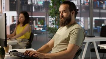 Meticulous staff member imputing data on computer in office. Adept worker at desk focused on typing company statistical numbers, working hard to finish job before deadline, camera A video