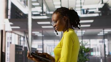 computador cientista trabalhando, fazendo Programas depuração usando caderno, solução de problemas erros. mulher em pé dentro escritório, fixação codificação problemas usando computador portátil, resolução tarefas, Câmera uma video