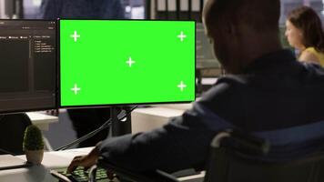 Man with disability in inclusive workplace working with machine learning tech on green screen computer. African american IT expert with paraplegia in wheelchair works with data on mockup PC, camera A video