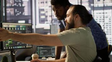 Manager correcting programmer mistakes while conducting code review to fix errors, identifying technical issues with company software. Team leader supervising IT staff member optimizing code, camera A video