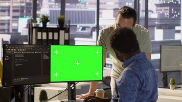 System administrator does software debugging on isolated screen PC, asking for help from coworker. Zoom in on admin fixing coding mistakes on chroma key computer, being assisted by colleague, camera A video