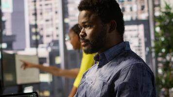System administrator at work creating machine learning models that can process and analyze data. Close up of african american IT expert programming in office using PC, camera A video