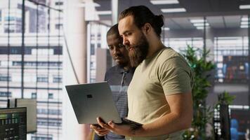 Programmer and colleague conducting experiments and tests to optimize machine learning models for performance and accuracy. IT staff members in office analyzing and interpreting complex data, camera A video