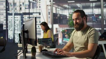 Employee looking at PC monitor, drinking coffee, checking data needed for finding business insights and finishing project task. Man analyzing data on computer, enjoying beverage, camera B video