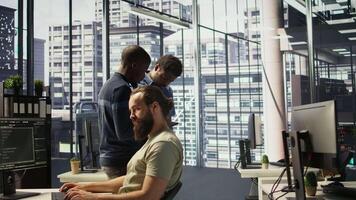 Technician and colleague using device for managing cloud computing platforms training machine learning models. IT staff members in office monitoring company systems using tablet, camera B video
