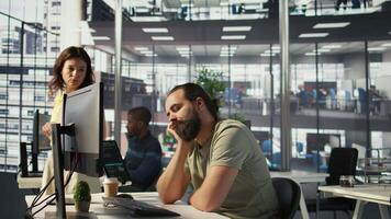 Fatigued software engineer caught asleep at desk by manager while developing artificial intelligence tech. Team leader waking up lazy worker while training predictive models, camera B video