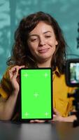 Vertical Woman filming tech tutorial on how to repair damaged mockup tablet using professional camera. Engineer teaching fans to install operating system on green screen device, recording with gear, camera A video