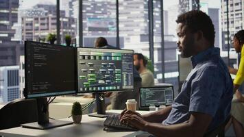 System administrator at work creating machine learning models that can process and analyze data. Close up of african american IT expert programming in office using PC, camera B video