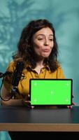 Vertical Happy internet star being sponsored by partnering brand to do mockup tablet unboxing content. Smiling tech specialist does influencer marketing, presenting green screen device, camera B video