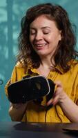 Vertical Happy tech content creator filming technology review of newly released VR glasses, unpacking them and presenting specs to fans. Jolly woman showing virtual reality headset to subscribers, camera A video