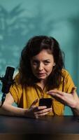 Vertical Streamer doing live broadcast, reading juicy text messages from mobile phone screen. Influencer commenting about social media posts on cellphone, talking with viewers, camera B video