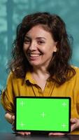 Vertical Cheerful media star being sponsored by partnering brand to do mockup tablet unboxing content. Upbeat tech expert does influencer marketing, presenting green screen device, camera A video
