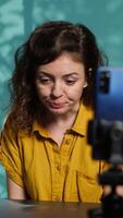 Vertical Content creator using smartphone on phone holder to shoot intro for vlog channel on online platforms. Internet star warmly welcoming dedicated fanbase, filming with cellphone, camera A video