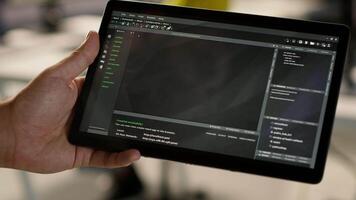 Software engineer using tablet to design algorithms that enable machines to learn from data. Close up of admin in office training and deploying large scale deep learning models with device, camera A video