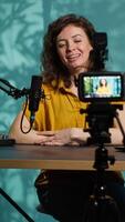 Vertical Professional camera used for recording woman chatting with online audience, filming in home studio. Media star discussing with fans during live broadcast stream recorded with advanced gear, camera A video