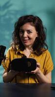 Vertical Happy tech content creator filming technology review of newly released VR glasses, unpacking them and presenting specs to fans. Jolly woman showing virtual reality headset to subscribers, camera B video