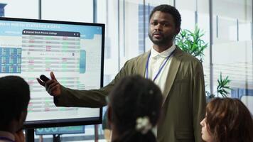Business professional staff gather to review project development progress, detailed reports and statistics on interactive board to ensure strategic objectives. Diverse work team in meeting. Camera A. video