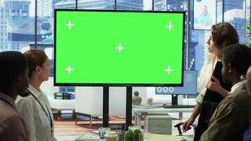 Diverse group of startup employees looking at green screen on an interactive board, meeting to discuss ideas and details to ensure organizational progress. Forecast affiliates in office. Camera A. video